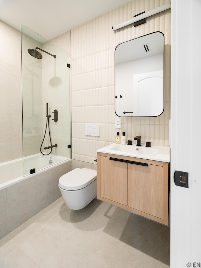 bathroom with vanity, toilet, tile walls, tiled shower / bath combo, and visible vents