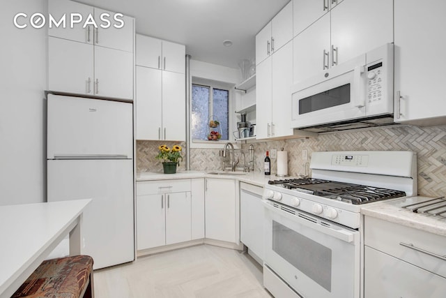 kitchen with a sink, tasteful backsplash, white appliances, and light countertops