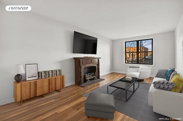 living area featuring a brick fireplace, baseboards, visible vents, and wood finished floors
