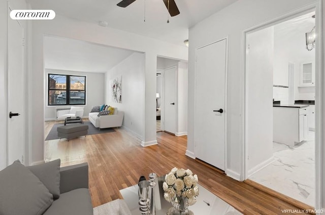 living room featuring a ceiling fan, baseboards, visible vents, and light wood-type flooring