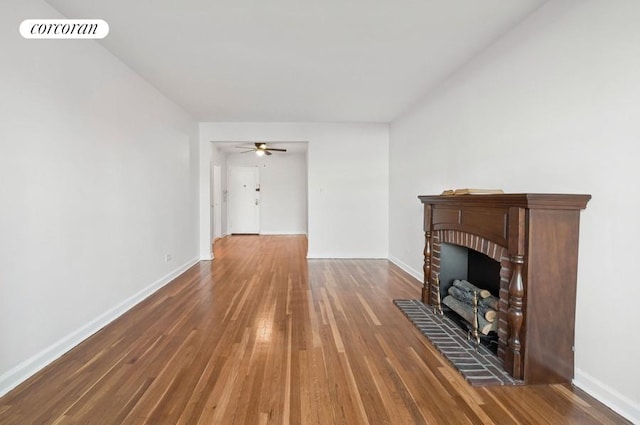 unfurnished living room with visible vents, baseboards, wood finished floors, and a fireplace