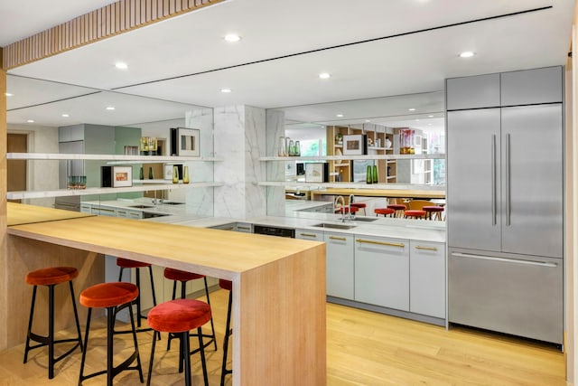 bar featuring a sink, recessed lighting, light wood-style flooring, and built in fridge