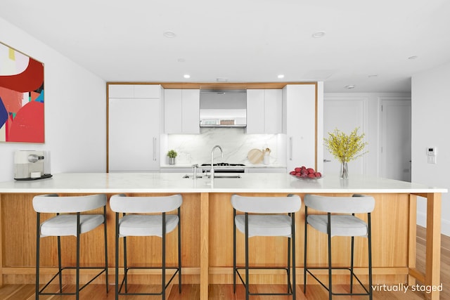 kitchen featuring light countertops, decorative backsplash, white cabinets, and light wood finished floors
