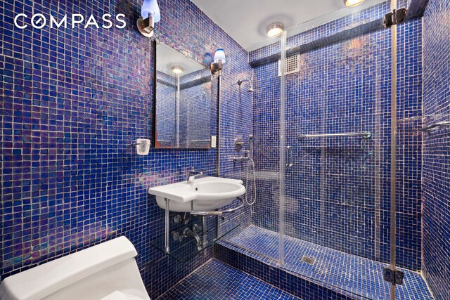 1025 5th Ave Unit 7As, New York City, NY 10028 - bathroom with tile walls, a shower stall, a sink, and tile patterned floors
