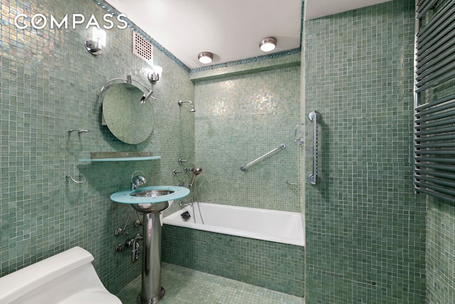 1025 5th Ave Unit 7As, New York City, NY 10028 - full bath featuring tile walls, toilet, tiled shower / bath combo, and a towel warming rack