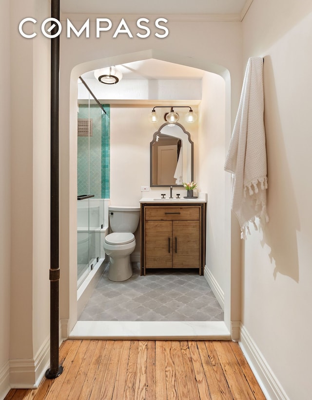 bathroom featuring toilet, a shower stall, wood finished floors, and vanity