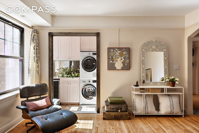 200 E 16th St Unit 5Lm, New York City, NY 10003 - living area featuring stacked washer / drying machine, arched walkways, light wood-style floors, and beverage cooler