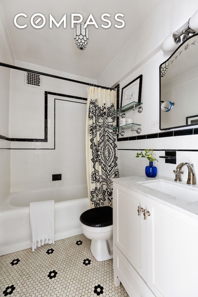 bathroom featuring vanity, shower / tub combo with curtain, toilet, tile walls, and tile patterned floors