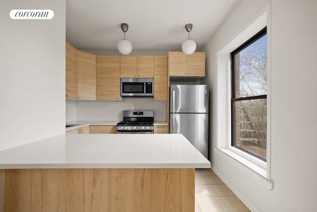 kitchen featuring light brown cabinetry, light countertops, appliances with stainless steel finishes, and tasteful backsplash