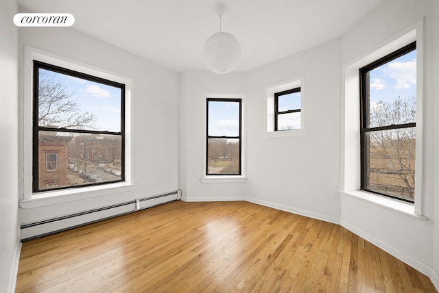 unfurnished room with baseboards, a baseboard heating unit, light wood-style flooring, and visible vents