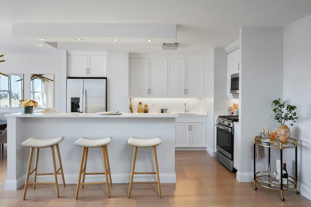 kitchen with white cabinets, a kitchen breakfast bar, and appliances with stainless steel finishes
