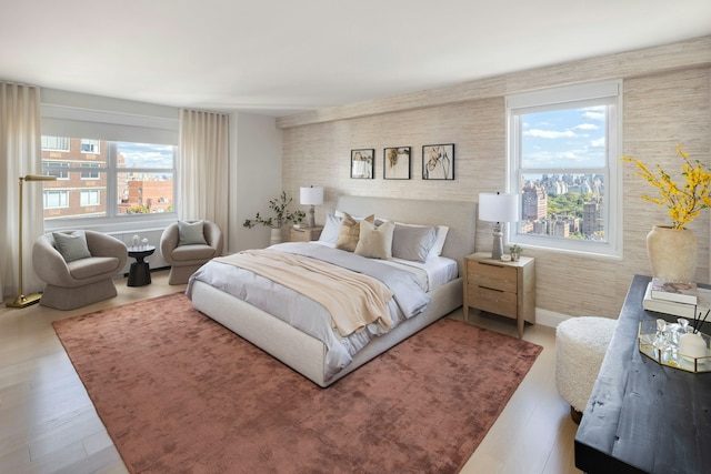 bedroom with baseboards, an accent wall, and wood finished floors