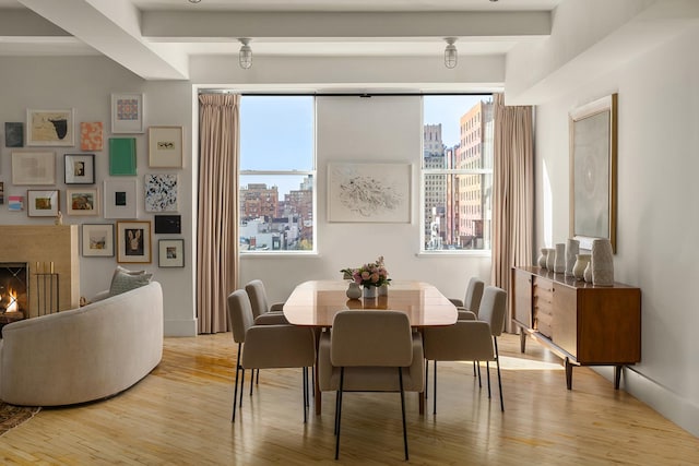 dining space with a wealth of natural light, beam ceiling, and wood finished floors