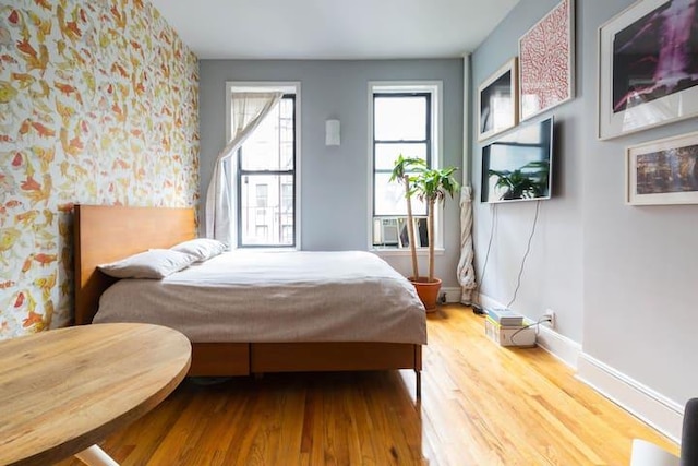 186 E 2nd St Unit 2, New York City, NY 10009 - bedroom with wallpapered walls, wood finished floors, baseboards, an accent wall, and cooling unit