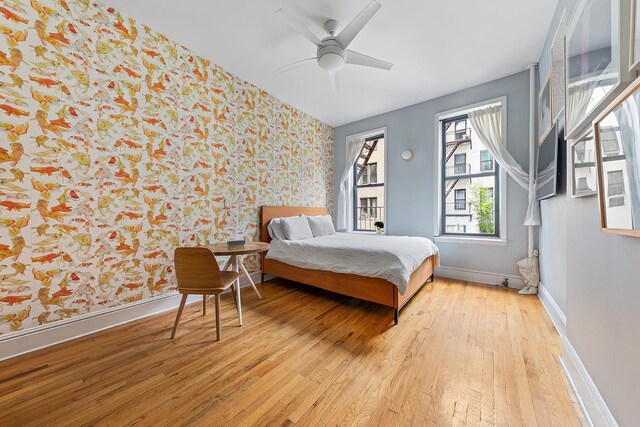 186 E 2nd St Unit 2, New York City, NY 10009 - bedroom featuring wallpapered walls, light wood-style flooring, baseboards, and ceiling fan