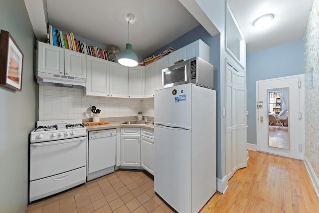 186 E 2nd St Unit 2, New York City, NY 10009 - kitchen featuring white appliances, under cabinet range hood, backsplash, light countertops, and a sink
