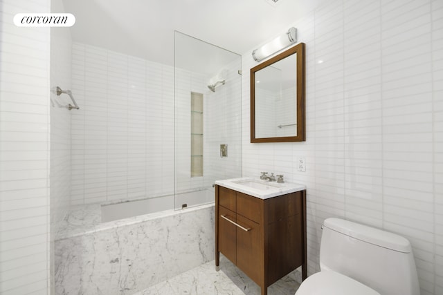 bathroom featuring vanity, a combined bath / shower with marble appearance, toilet, and tile walls