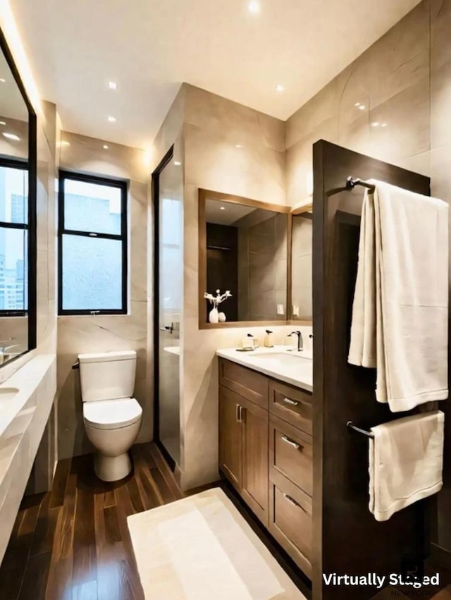 212 E 48th St Unit 5-C, New York City, NY 10017 - bathroom featuring wood finished floors, vanity, tile walls, toilet, and a tub to relax in