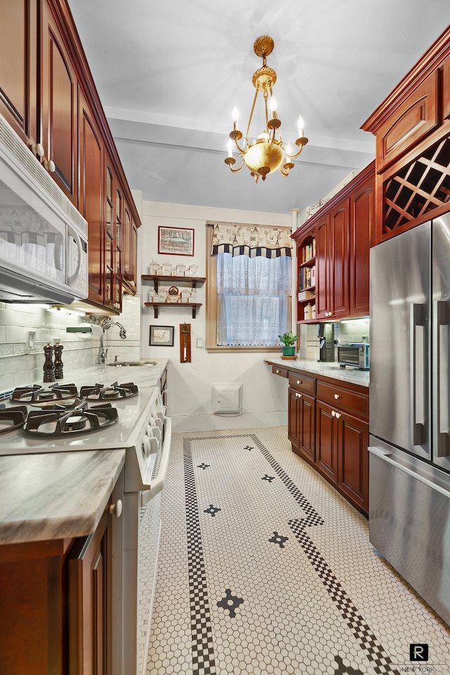 kitchen with open shelves, white appliances, reddish brown cabinets, a sink, and a notable chandelier