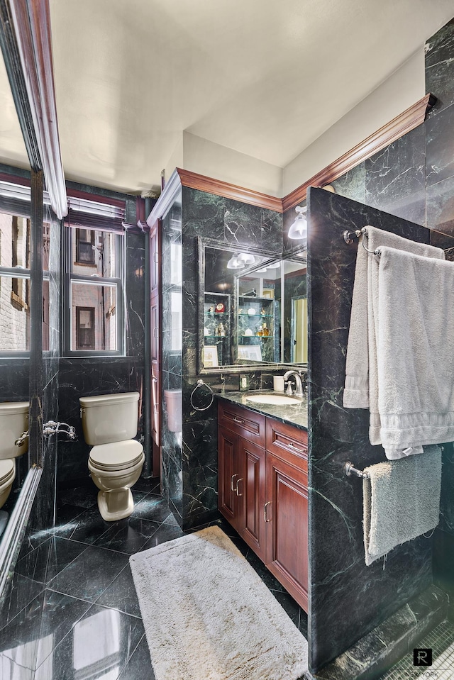 full bathroom with vanity, toilet, and tile walls