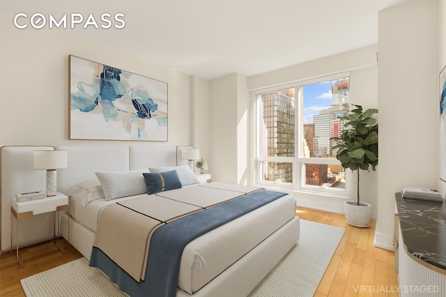 350 W 42nd St Unit 26G, New York City, NY 10036 - bedroom with light wood-style flooring, a city view, and baseboards