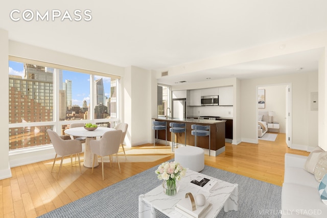350 W 42nd St Unit 26G, New York City, NY 10036 - living room featuring light wood-style flooring, a skyline view, and baseboards