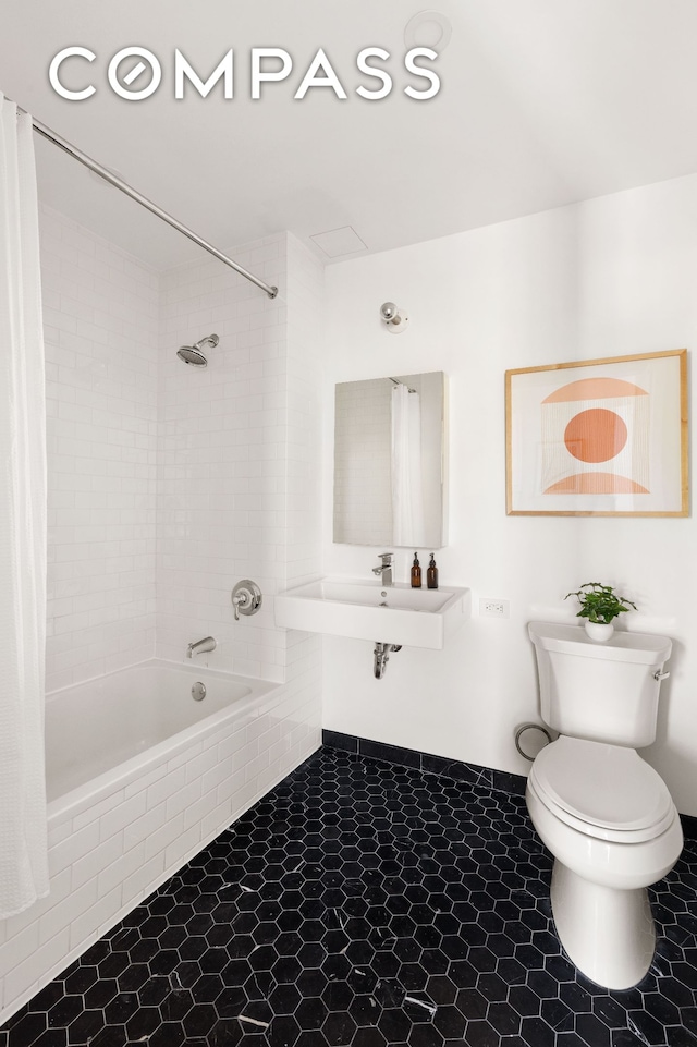full bath with a sink, tiled shower / bath, and toilet