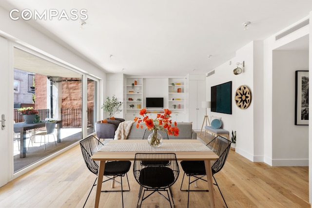 dining area with baseboards, light wood finished floors, built in shelves, and visible vents