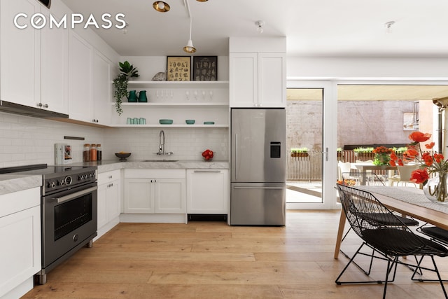kitchen featuring tasteful backsplash, a sink, under cabinet range hood, stainless steel appliances, and white cabinetry
