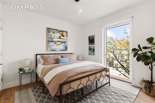 bedroom with baseboards, access to outside, and wood finished floors