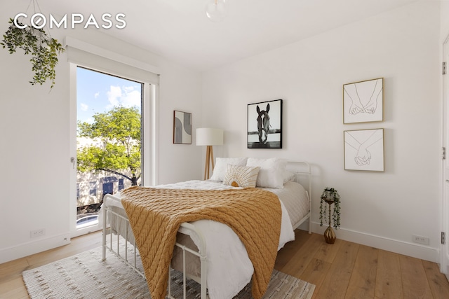 bedroom featuring access to outside, baseboards, and light wood-style floors