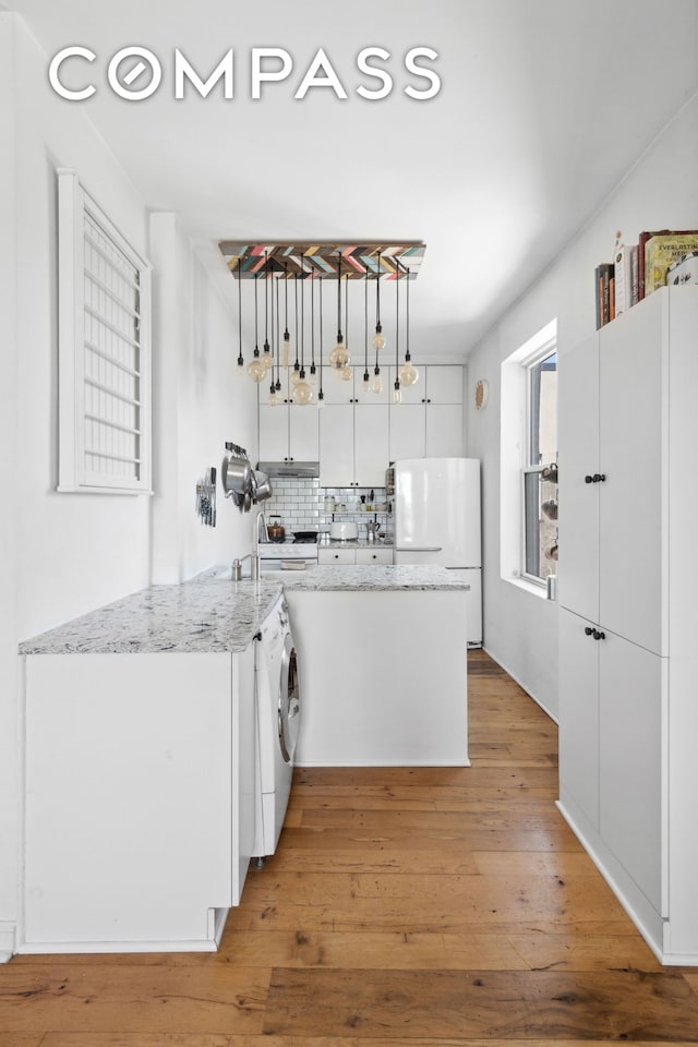kitchen featuring freestanding refrigerator, white cabinets, decorative backsplash, and light wood-type flooring