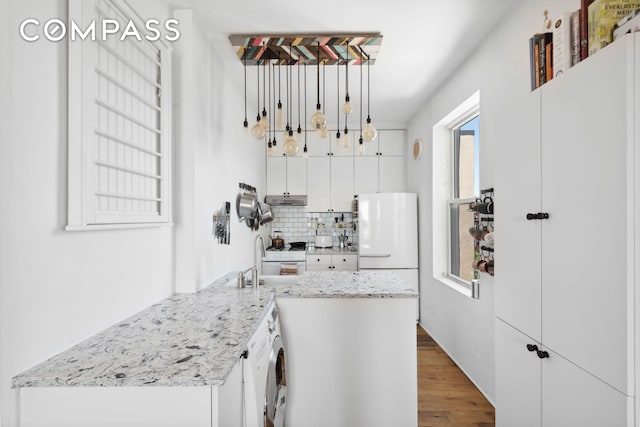kitchen with white cabinets, a sink, freestanding refrigerator, wood finished floors, and tasteful backsplash