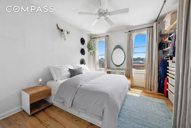 bedroom with ceiling fan, baseboards, and light wood-type flooring