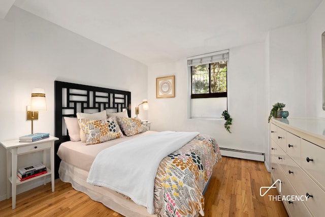 bedroom with a baseboard heating unit and light wood-style flooring
