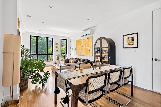 dining space featuring arched walkways, light wood-style flooring, recessed lighting, baseboards, and a wall unit AC