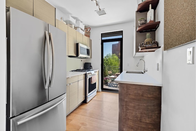 kitchen with open shelves, appliances with stainless steel finishes, a sink, light countertops, and light wood-style flooring