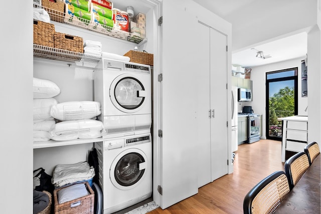 clothes washing area featuring light wood-type flooring, laundry area, and stacked washer and dryer