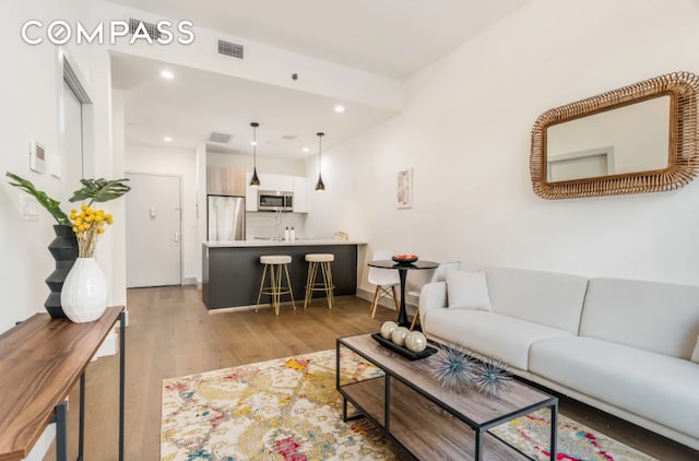 living room featuring visible vents, recessed lighting, and light wood finished floors