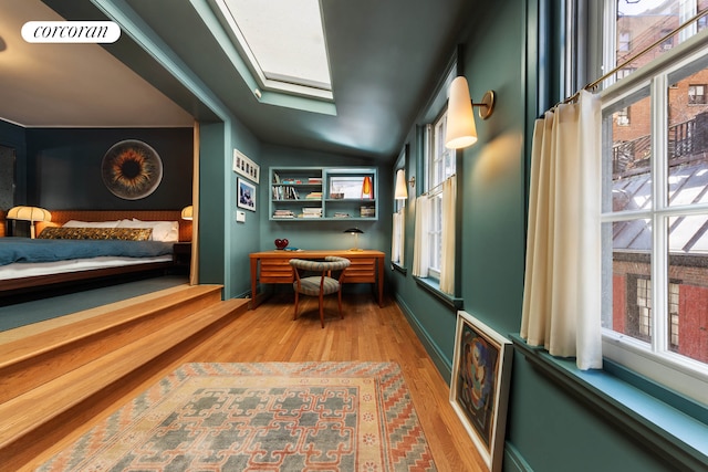 sitting room featuring wood finished floors, a skylight, and lofted ceiling