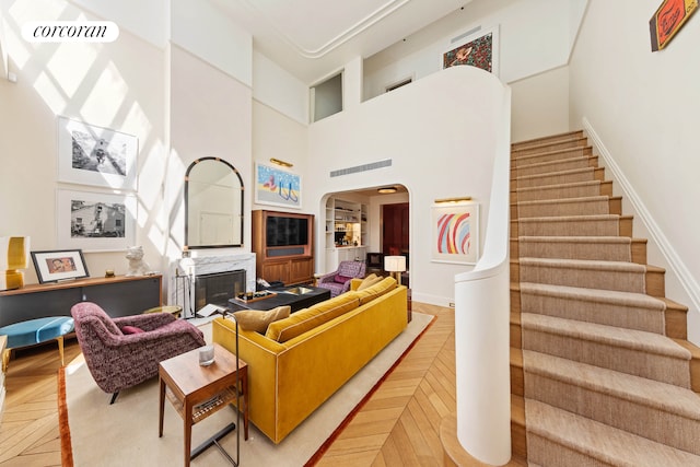 living room featuring a high ceiling, arched walkways, stairway, a premium fireplace, and baseboards
