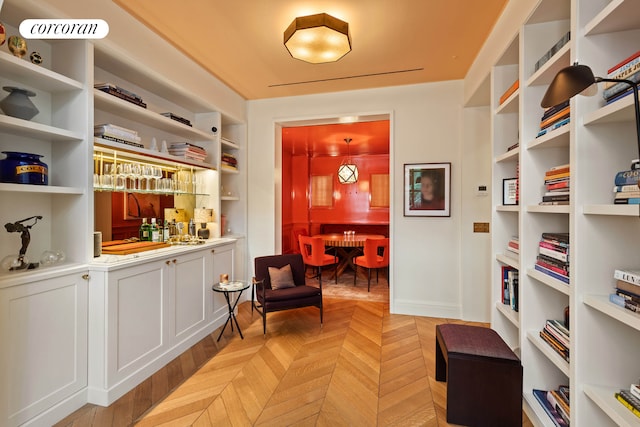 sitting room featuring bar with sink and built in shelves