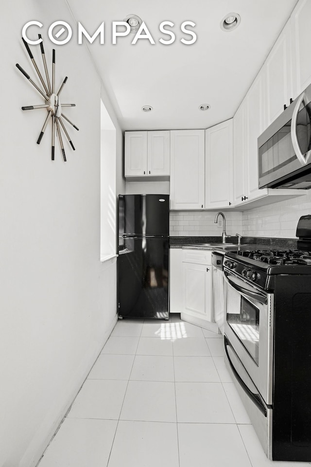 kitchen featuring light tile patterned flooring, dark countertops, white cabinetry, backsplash, and stainless steel appliances