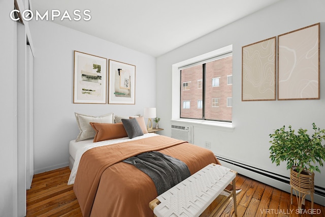 bedroom featuring wood-type flooring, baseboards, a wall mounted AC, and baseboard heating
