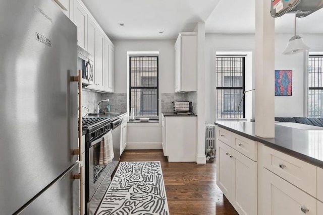 3117 Broadway Unit 1, New York City, NY 10027 - kitchen with appliances with stainless steel finishes, dark countertops, tasteful backsplash, dark wood finished floors, and white cabinets
