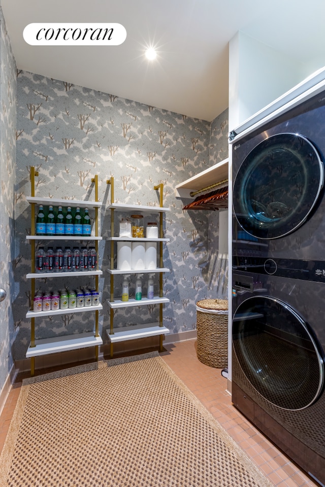 laundry area with wallpapered walls, laundry area, baseboards, and stacked washer and clothes dryer