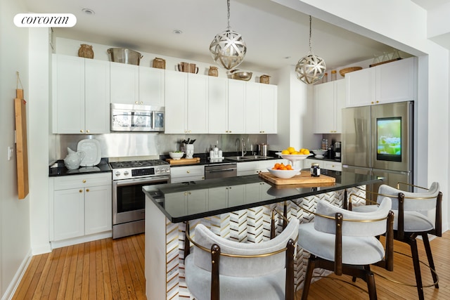 kitchen featuring dark countertops, appliances with stainless steel finishes, a sink, a breakfast bar area, and decorative backsplash