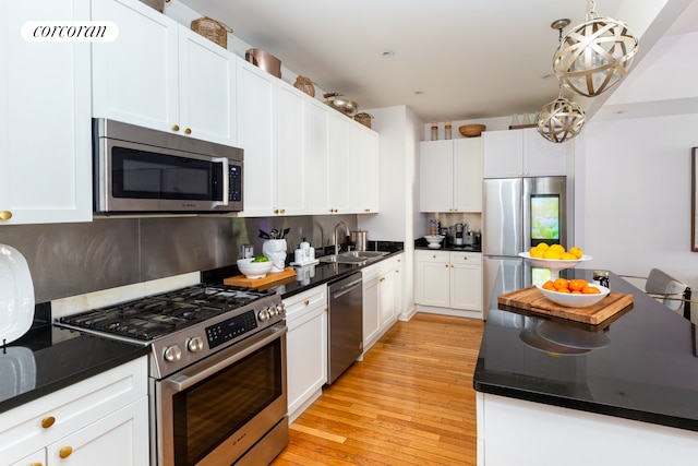 kitchen featuring decorative backsplash, dark countertops, white cabinets, a sink, and appliances with stainless steel finishes