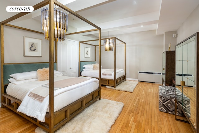 bedroom featuring an inviting chandelier, baseboard heating, light wood finished floors, and visible vents