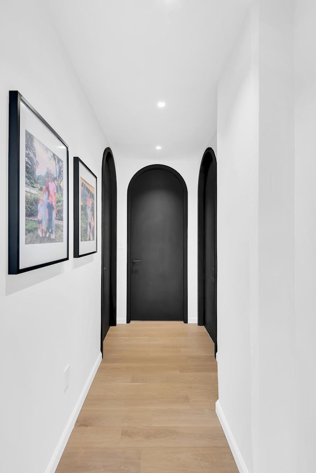 hall featuring recessed lighting, light wood finished floors, baseboards, and arched walkways